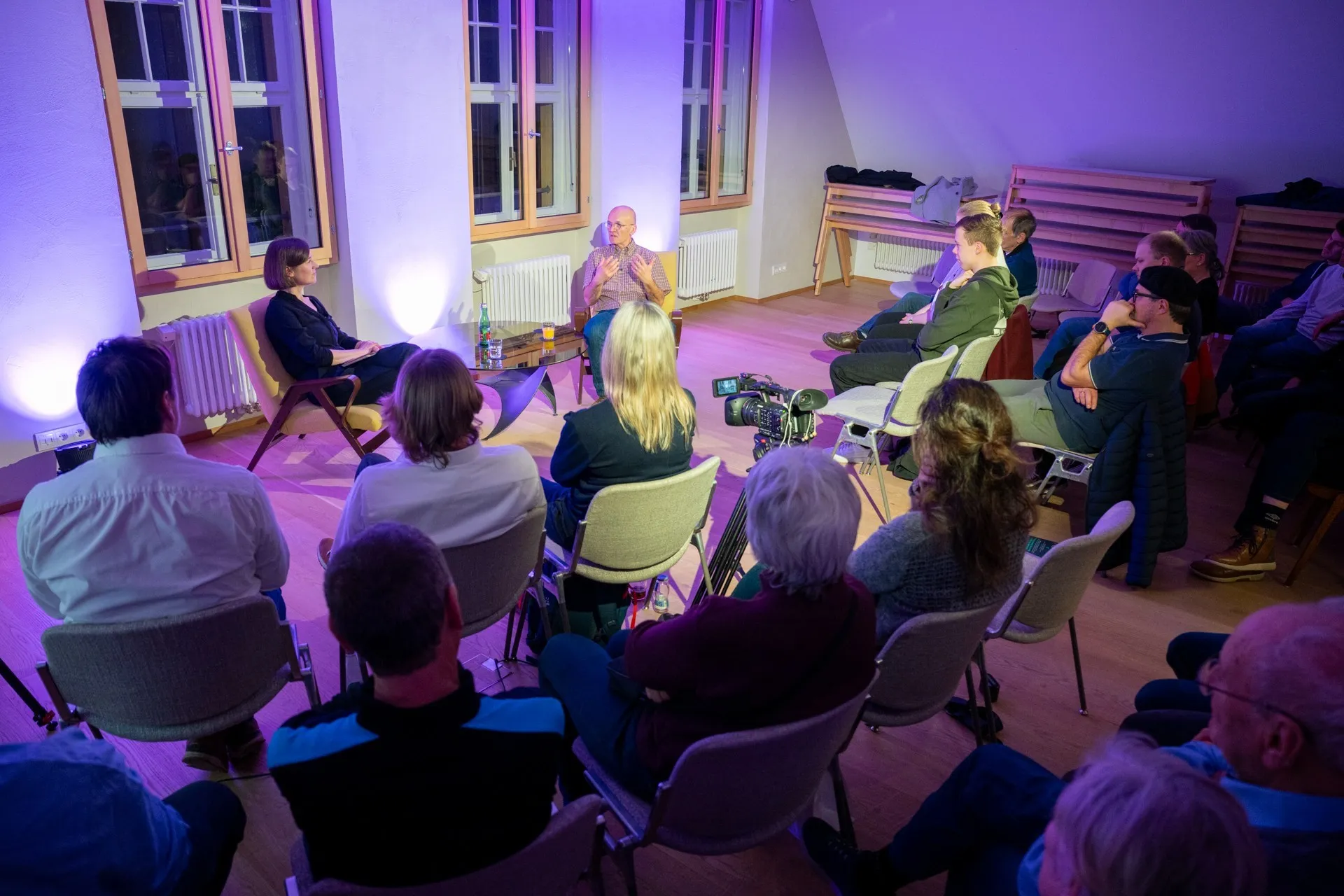 Moderatorin Carmen Jurkovic-Burtscher im Gespräch mit Holger Hansen. Publiukum im Hintergrund.