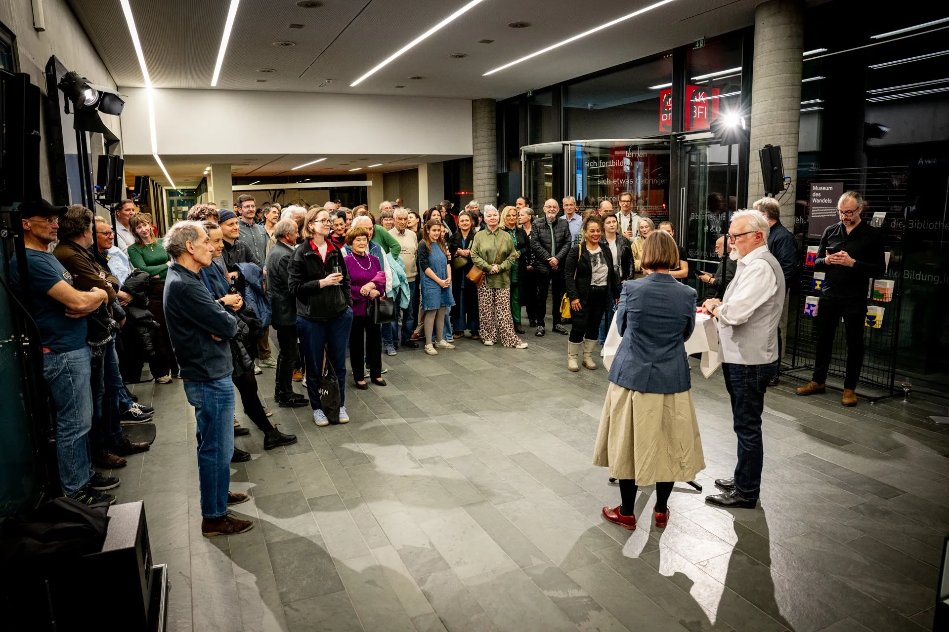 Besucherinnen und Besucher verfolgen aufmerksam das Programm bei der Vernissage zur Ausstellung „Museum des Wandels" der AK Vorarlberg.