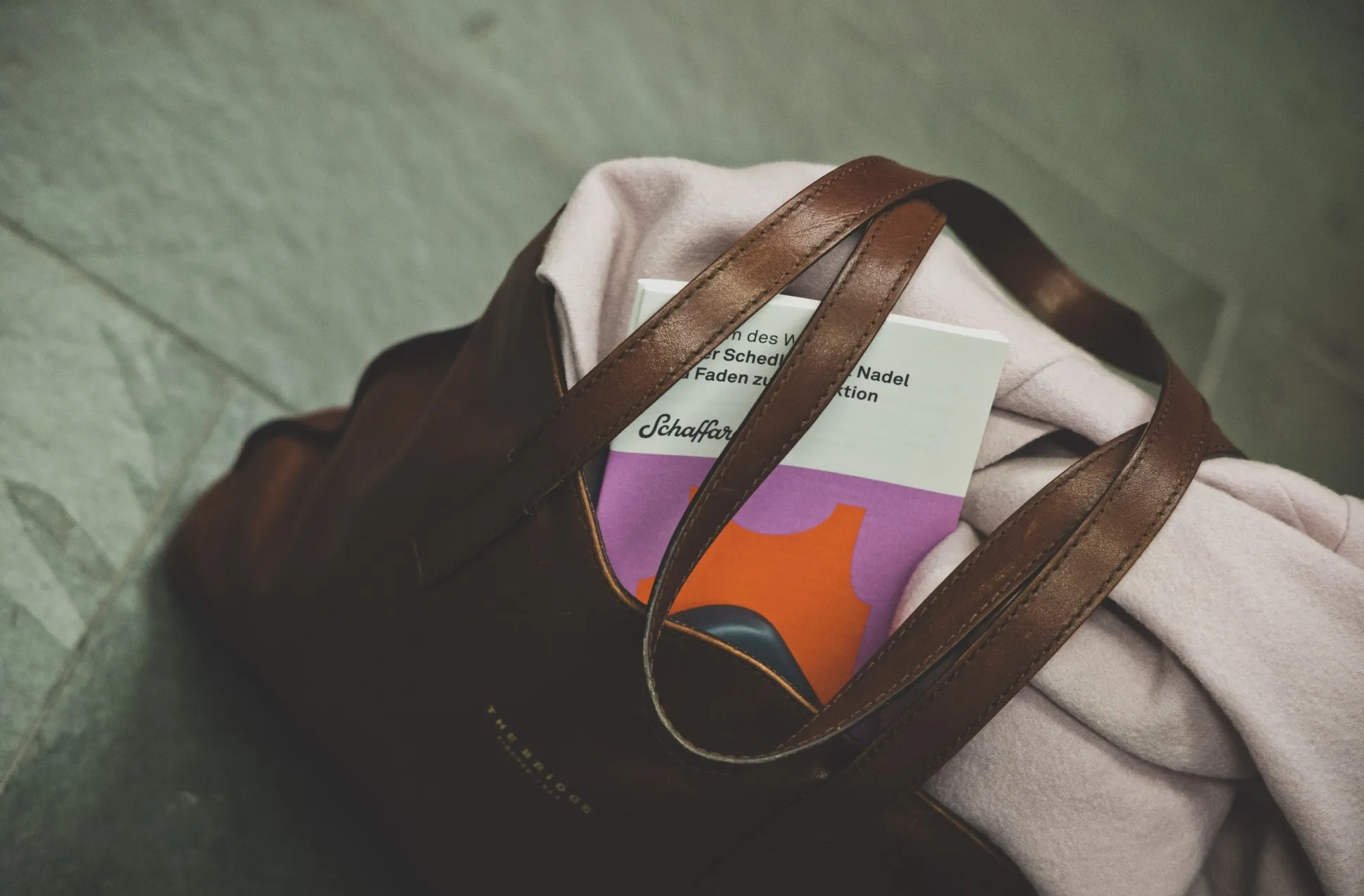 Ein Begleitheft zum Museum des Wandels schaut aus einer abgestellten Handtasche heraus.