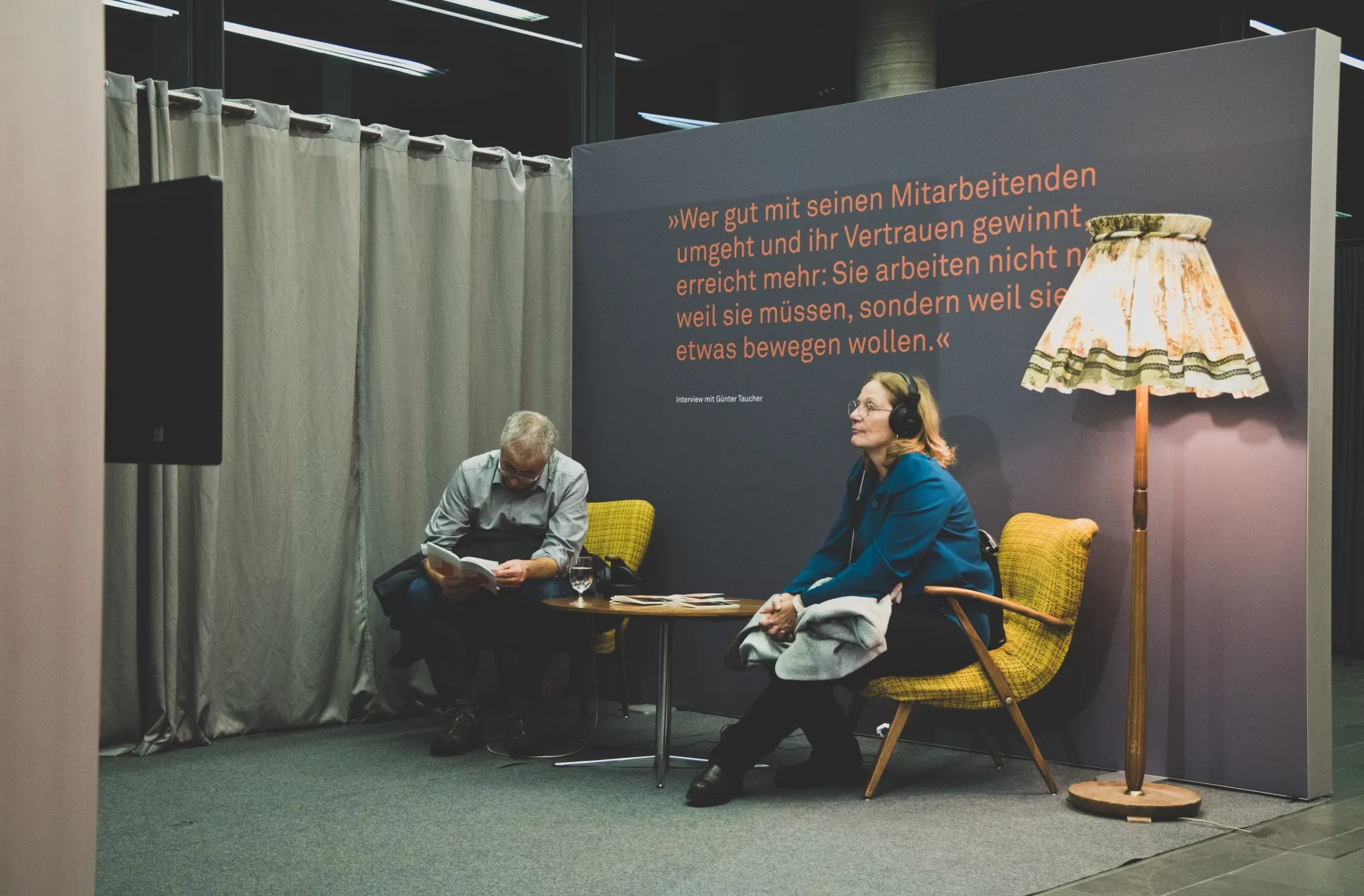 Zwei Besucher:innen der Ausstellung zu Günter Taucher sehen sich ein Videointerview mit ihm an.