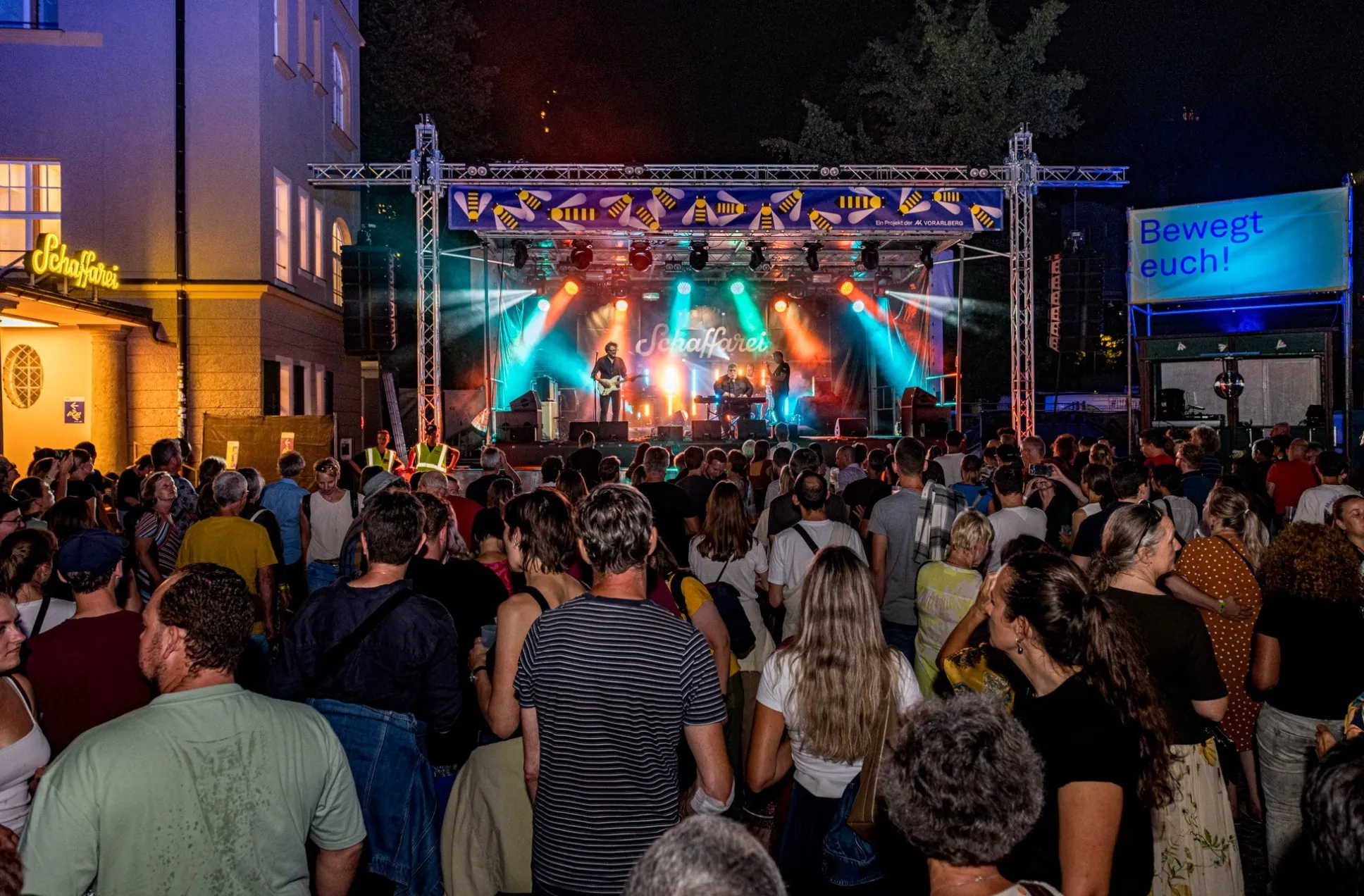 George Nussbaumer mit Band im Vordergrund ein gefüllter Platz im AK Quartier