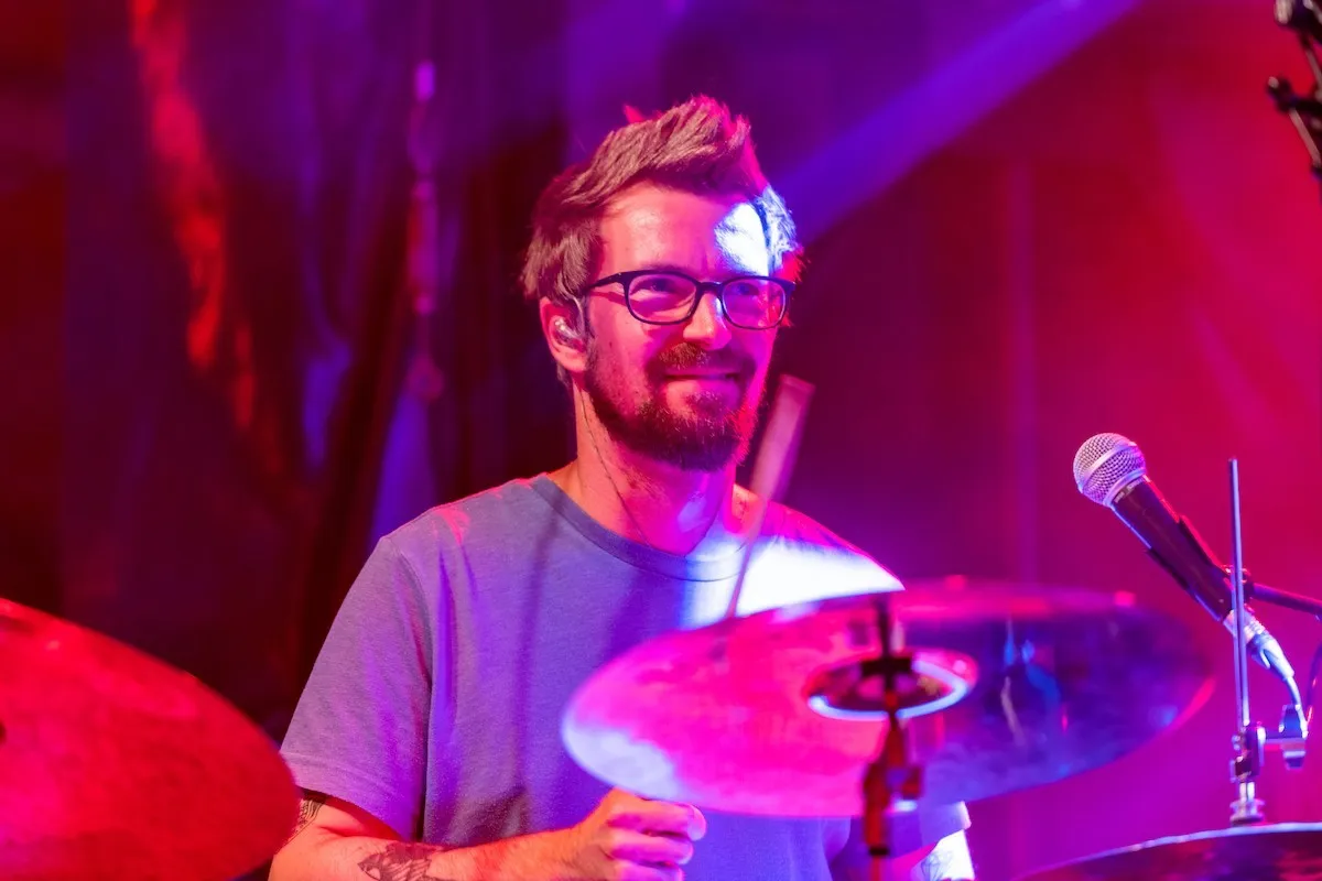 Schlagzeuger mit Brille auf der Schaffarei Bühne mit rotem Hintergrund