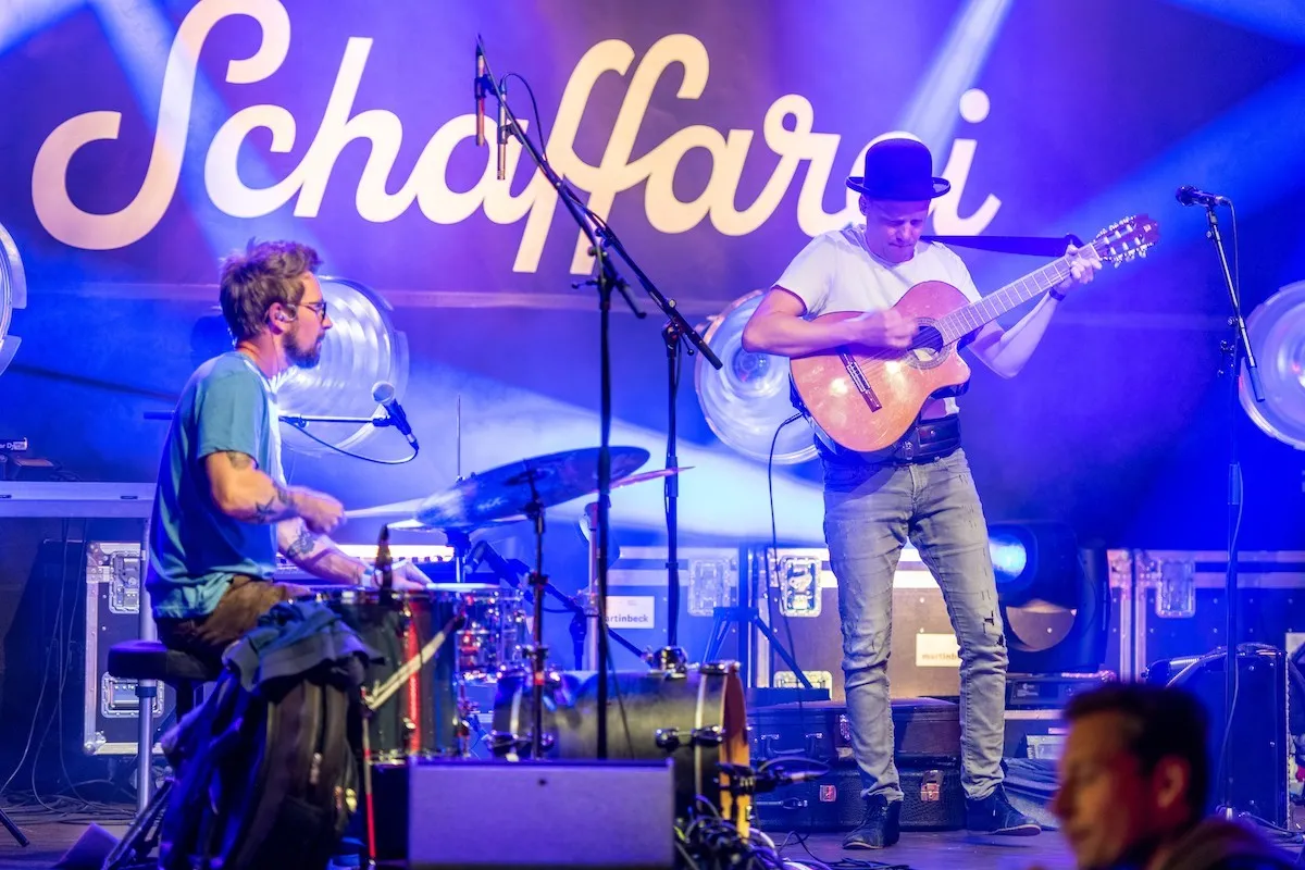 Schlagzeuger mit Brille und Sänger mit Hut und Gitarre auf der Schaffarei Bühne