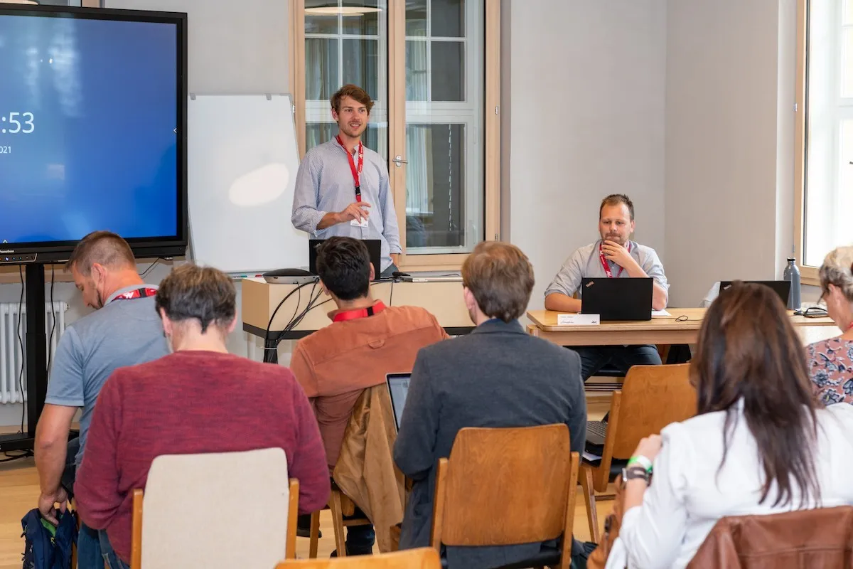 Zwei AK Mitarbeiter mit Bildschirm bei der Konferenz 2021 in einem Seminarraum der Schaffarei