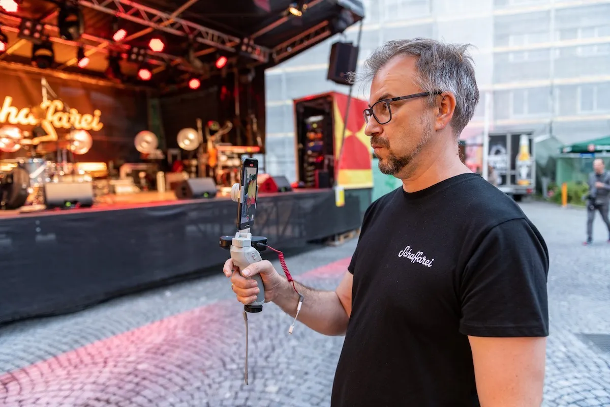 AK Mitarbeiter in schwarzem T-Shirt filmt die Schaffarei Bühne