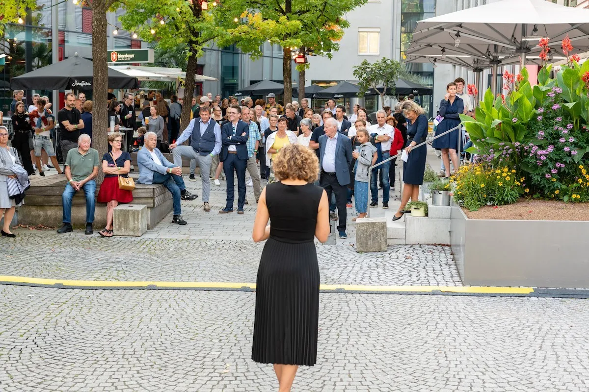 Moderatorin Raffarela Rudigier-Gerer in schwarzem Kleid von hinten und vorne das Publikum bei der Schaffarei Eröffnung 2021