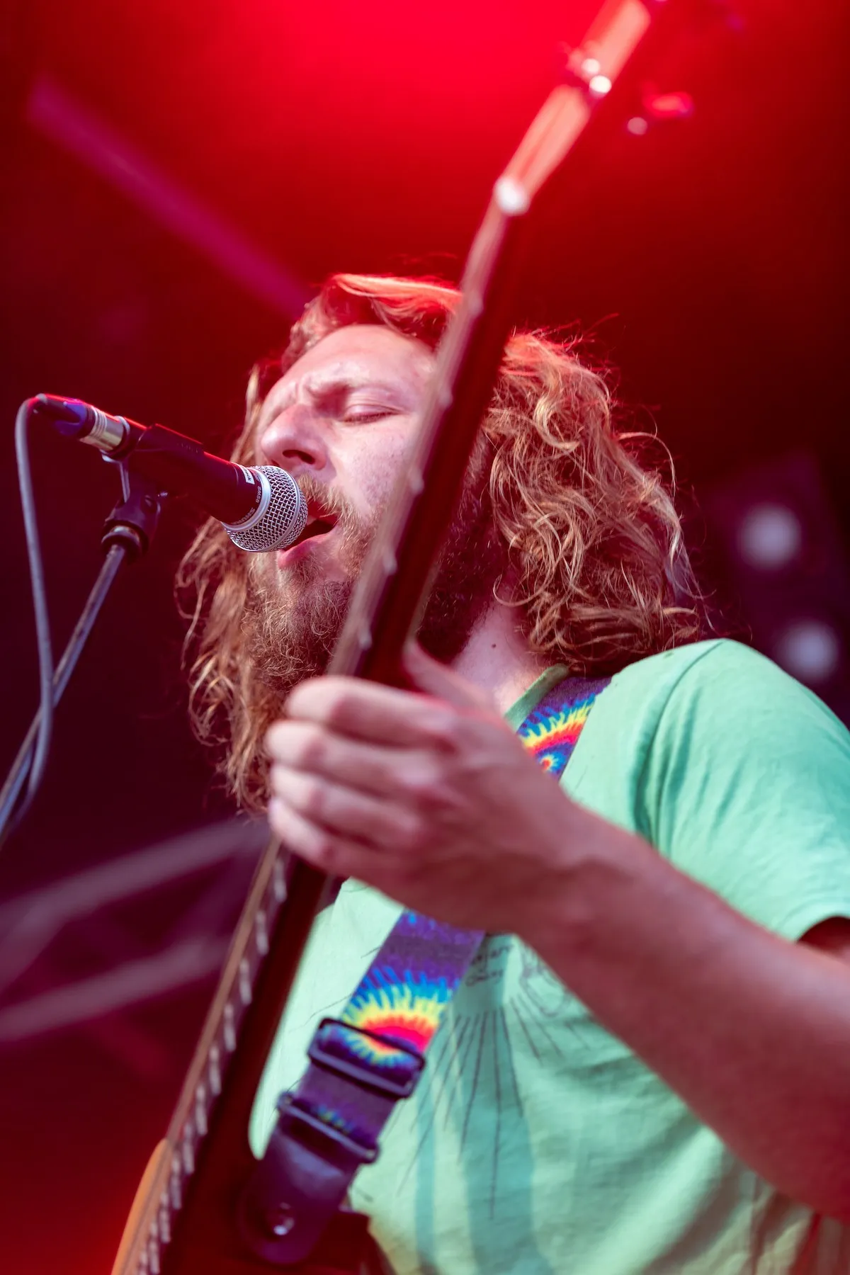 Sänger in grünem T-Shirt mit Gitarre auf der Schaffarei Bühne