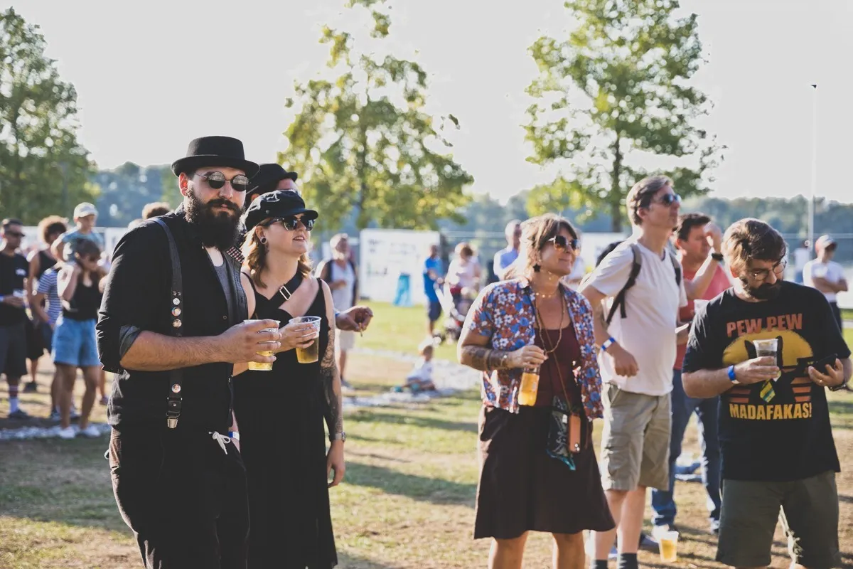 Gruppe von Personen mit Sonnenbrillen und Getränken in der Hand vor der Schaffarei Bühne