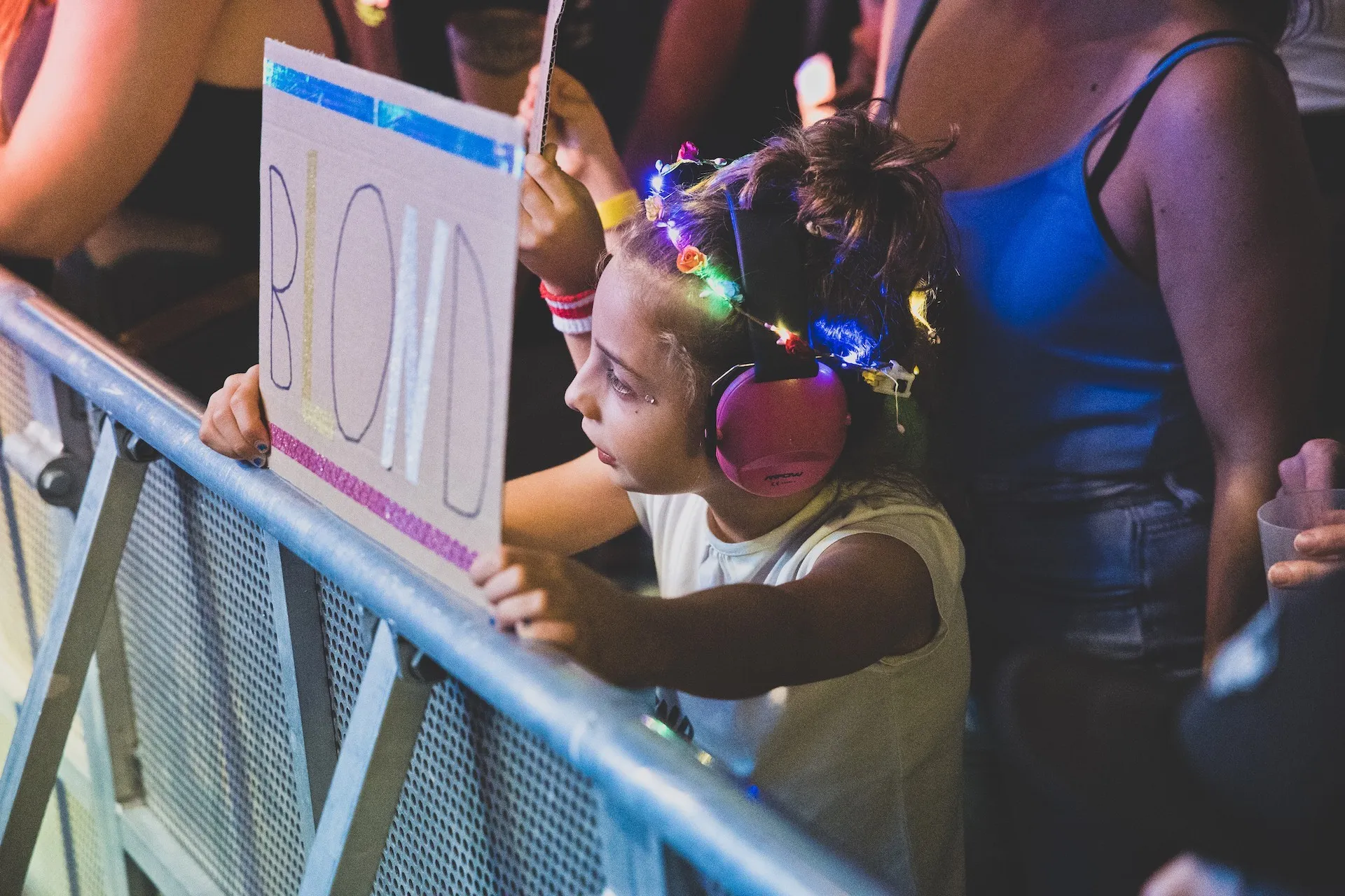 Kind mit Kopfhörer und Leuchtband im Haar mit Plakat vor der Schaffarei Bühne