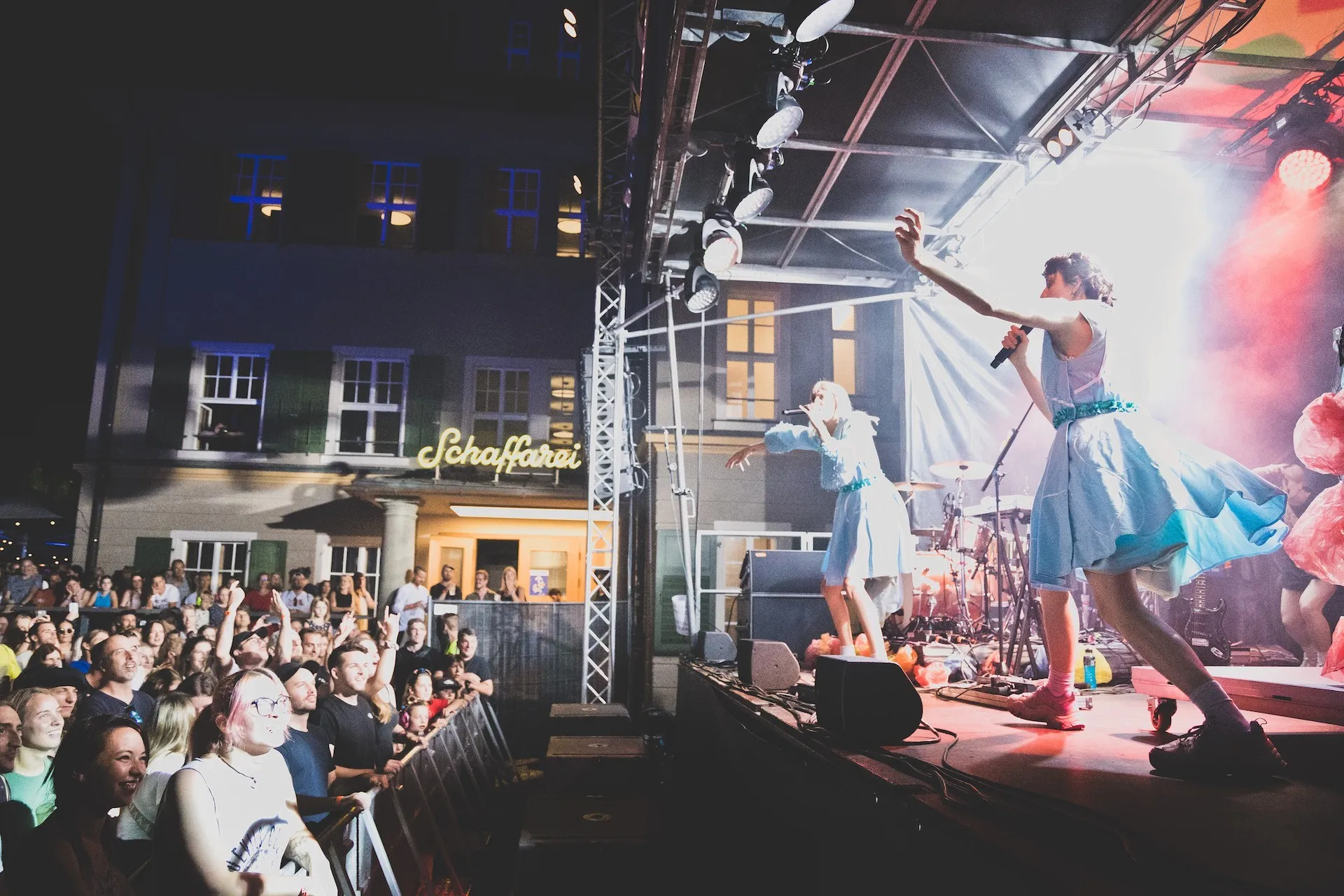 Band singend auf der Bühne mit Publikum im Vordergrund