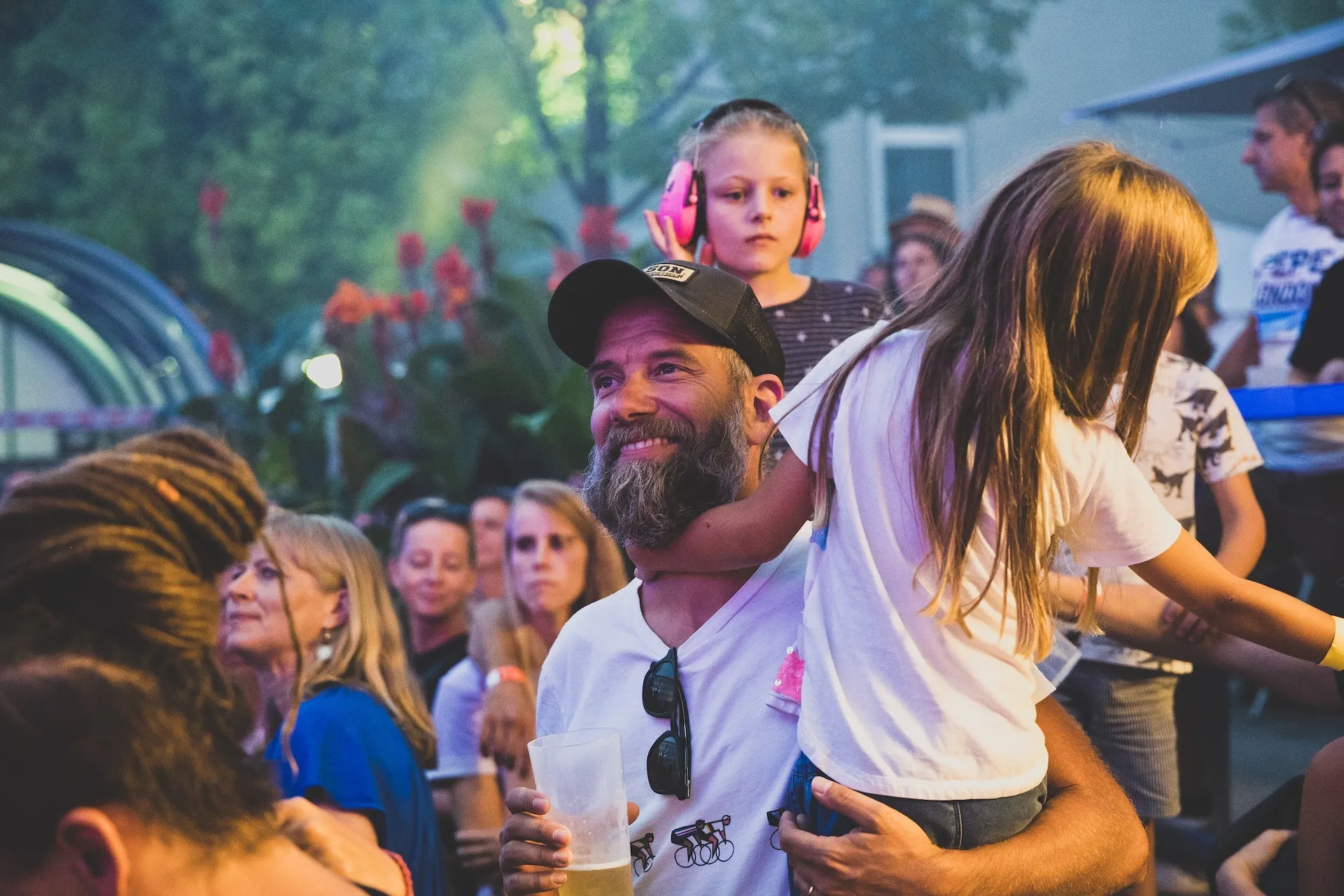 Mann mit Bart und Kind auf dem Arm und im Hintergrund mehrere Menschen