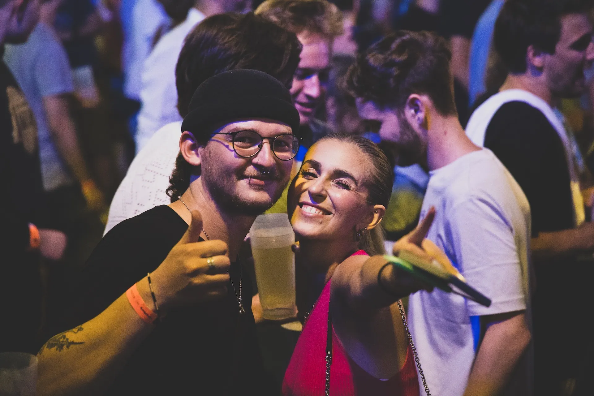 Zwei lächelnde Personen mit Daumen nach oben zeigend und Getränke in der Hand