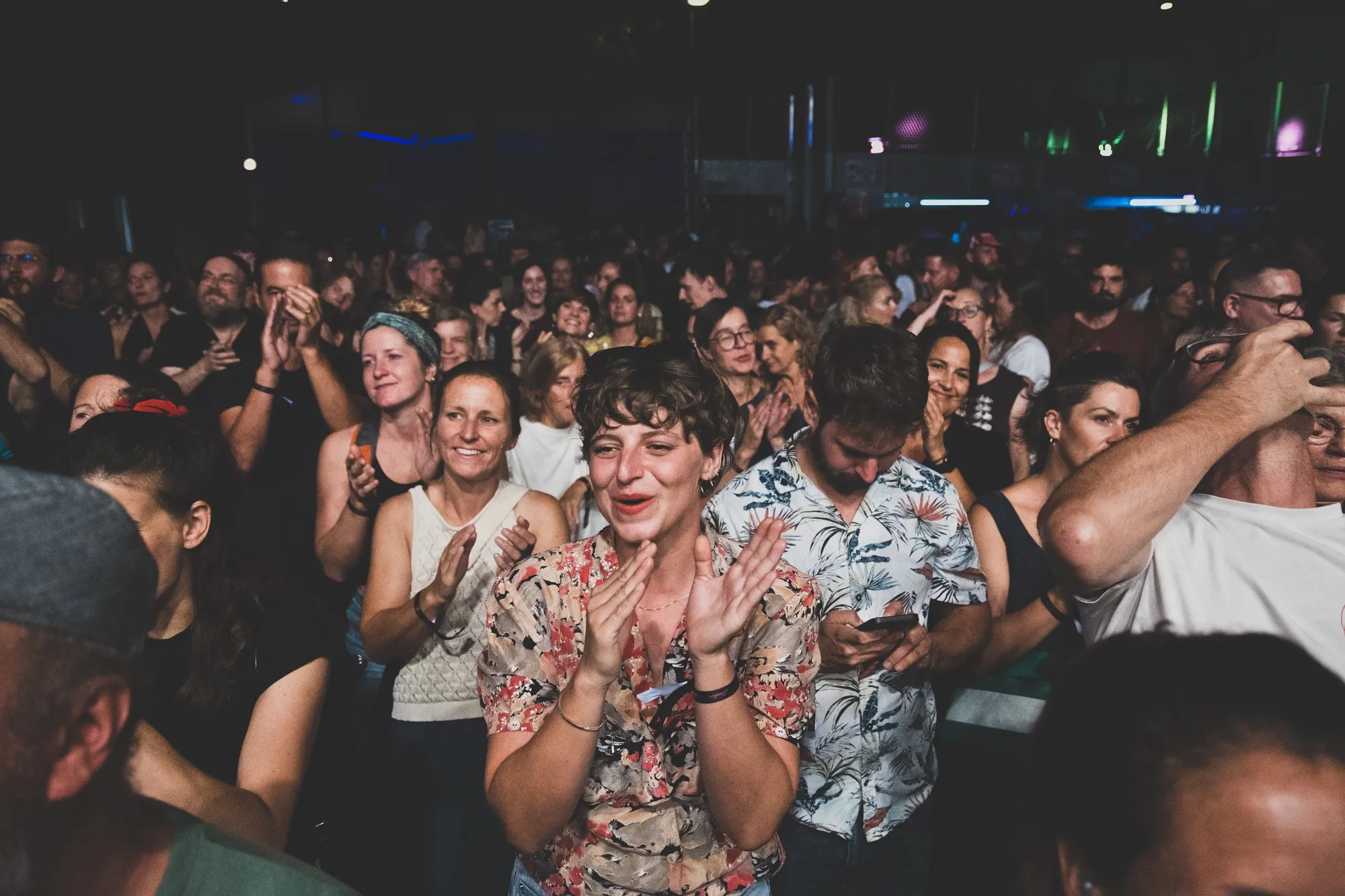 Klatschende Frau im Vordergrund und im Hintergrund eine Menschenmenge