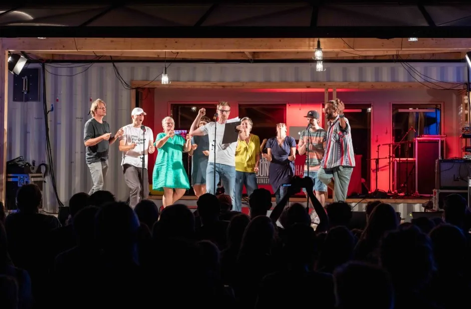 Menschen stehen auf einer Bühne und das Publikum ist zu sehen